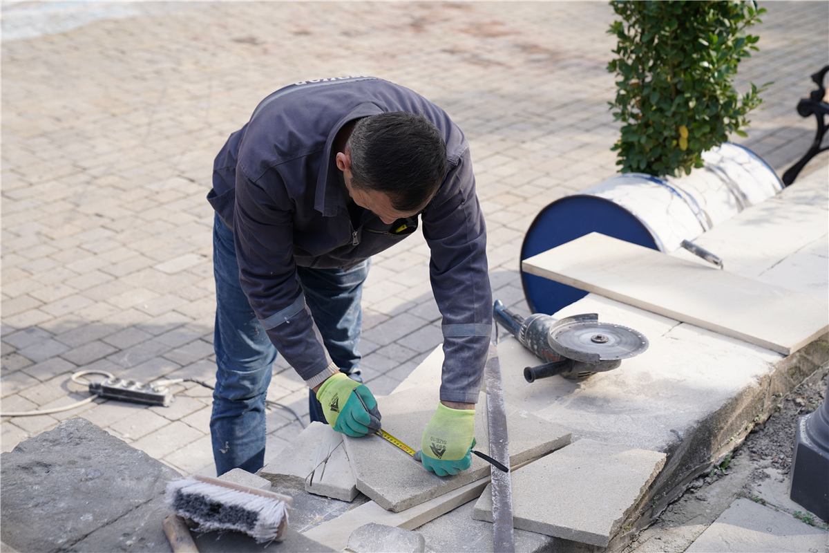 Ouvrier de Pavage Mik prenant des mesures sur un chantier de pavé-uni